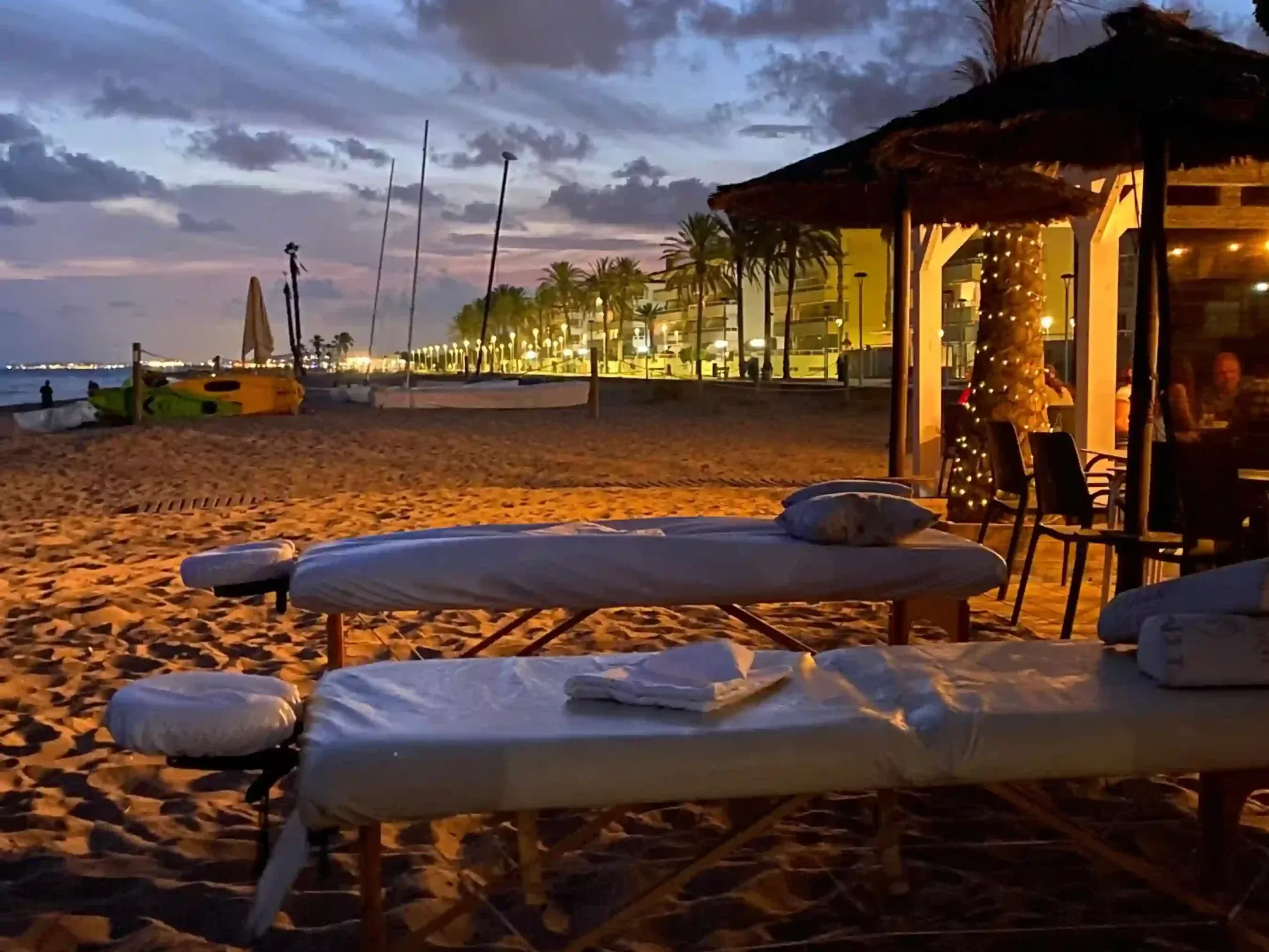 Chiringuito en la playa, frente el mar. Hay dos camillas preparadas para ofrecer un masaje en pareja.