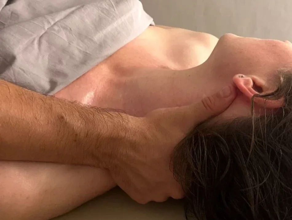 Pase de masaje californiano sobre nuca. Una mano abraza la nuca desplazándose lentamente por toda la zona cervical de forma profunda y envolvente.